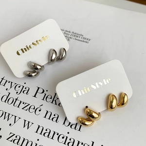 Détail de boucles d'oreilles torsadées en C, dorées et argentées, sur cartes présentoir