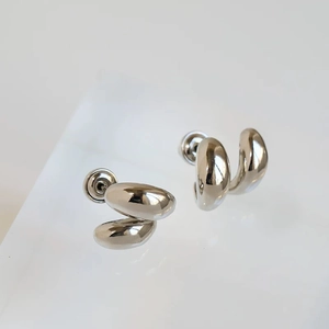 Détail macro de boucles d'oreilles argentées en forme de haricot avec fini miroir poli