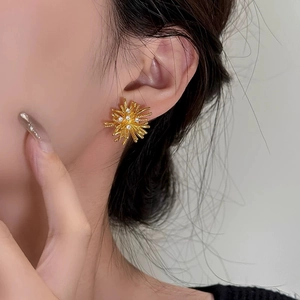 Elegant gold fireworks stud earrings with sparkling cubic zirconia on female model