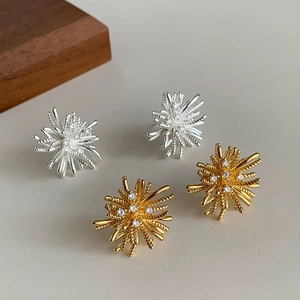 Macro detail of irregular fireworks stud earrings with zircon inlay in gold and silver