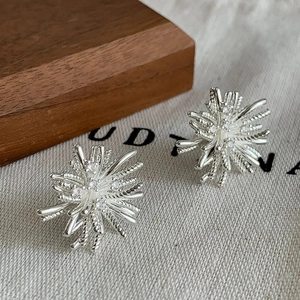 Detailed close-up of silver starburst earrings with sparkling cubic zirconia on wood