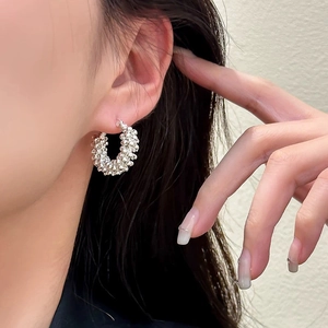 Detail of silver textured hoop earrings featuring a beaded metallic surface on a model