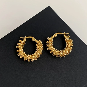 Detailed view of gold hoop earrings with a textured bead design on a black display box