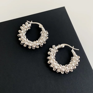 Detailed view of silver hoop earrings with a textured bead cluster design and metallic finish
