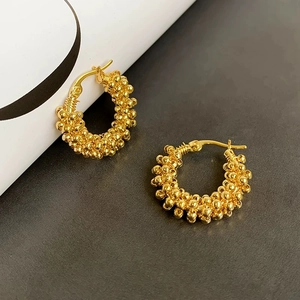 Detailed close-up of French style golden beaded hoop earrings with metallic texture