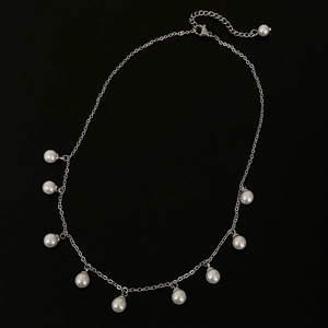 Elegante collana con frange di perle argentate su uno sfondo nero minimalista chic