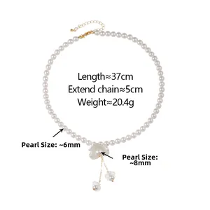 Détail du collier de perles avec pendentif fleur blanche et élégants glands perlés