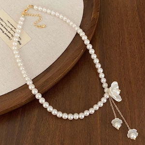 Élégant collier de perles avec pendentif fleur et accents dorés sur présentoir rétro
