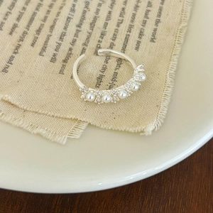 Detail of adjustable silver ring with five small white pearls and sparkling zircons