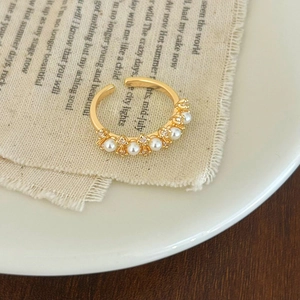 Detail of elegant gold open ring with five white pearls and sparkling rhinestones