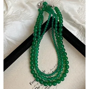 Three-layer green chalcedony beaded necklace with elegant silver clasp on white fabric