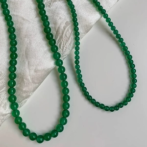 Detail of green chalcedony beaded necklace on white silk background for elegant look