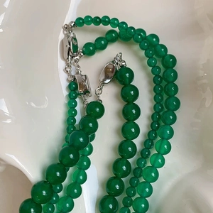 Macro detail of green chalcedony beaded necklaces in various bead sizes on white ceramic