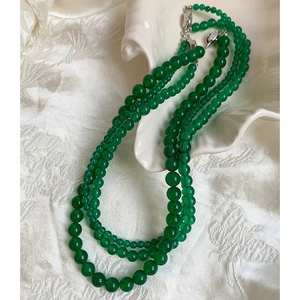 Macro shot of green chalcedony beaded necklaces with silver clasps on white silk
