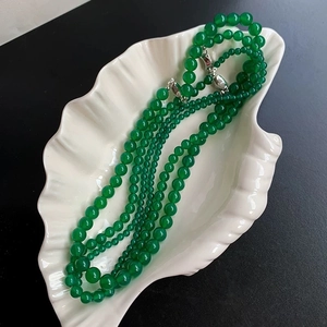 Detail of green chalcedony layered beaded necklace on a white leaf-shaped tray