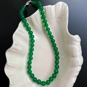 Close-up of green chalcedony beaded necklace with silver clasp in a shell-shaped tray