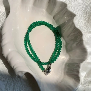 Close-up of green chalcedony beaded necklace on shell tray showing polished gems and clasp