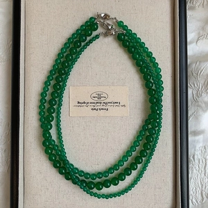 Close-up of green chalcedony beaded necklace with silver lobster clasp on a display tray