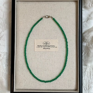 Detail of green chalcedony beaded necklace with elegant silver metal clasp design