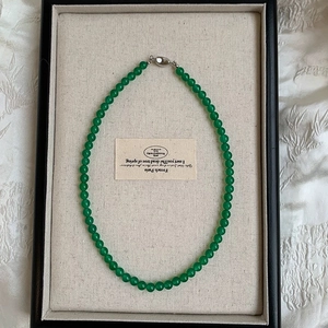 Close-up of green chalcedony bead necklace with silver clasp in a jewelry display tray