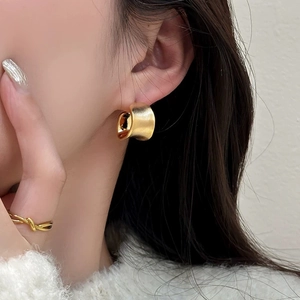 Minimalist irregular brushed gold hoop earrings worn by a model for an elegant look