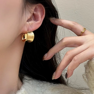 Detailed view of brushed gold irregular stud earrings with polished inner surface