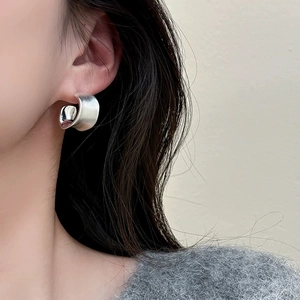 Detail of matte silver C-shaped earrings with brushed texture on female model
