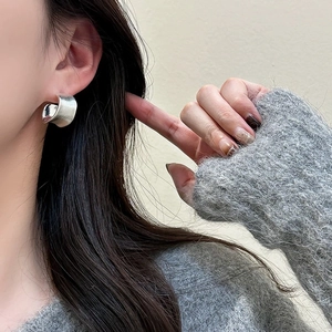 Close-up of minimalist silver irregular brushed earrings worn by a model