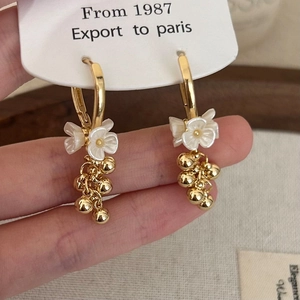 Vintage gold grape tassel earrings with white flower petals and pearls on a display card