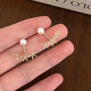 Gros plan détaillé de boucles d'oreilles nœuds dorées et perles tenues à la main