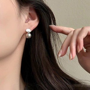 Close-up of minimalist silver metallic ball earrings worn by model for elegant style