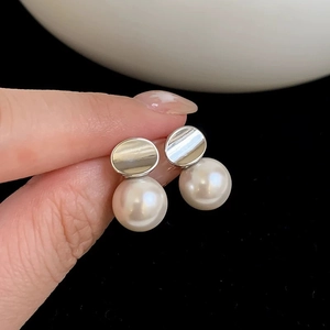 Macro detail of elegant round white pearl earrings with oval silver mirror finish base
