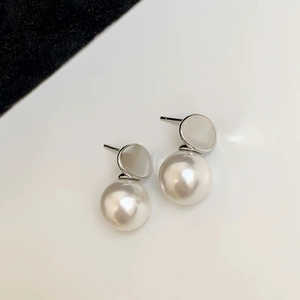 Detail of elegant pearl drop earrings featuring white mother-of-pearl and silver accents