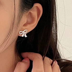 Gros plan de boucles d'oreilles nœud étincelantes avec zircons sur le mannequin