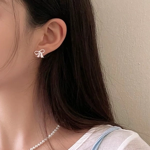 Gros plan d'une boucle d'oreille nœud en argent sertie de zircons sur un mannequin