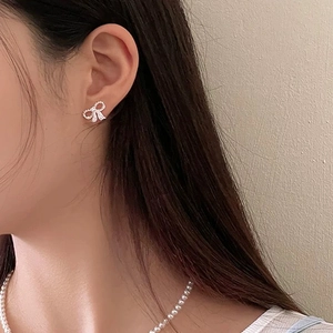 Gros plan de boucles d'oreilles nœud scintillant avec zircone sur un modèle féminin