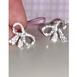Détail de boucles d'oreilles nœuds scintillantes serties de pierres en oxyde de zirconium