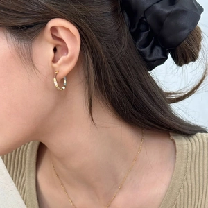 Detail of French vintage contrast color earrings and slim gold beaded necklace on a model