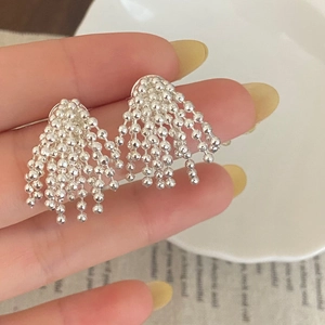 Silver bead tassel drop earrings with cascading chains shown on hand in a luxury style