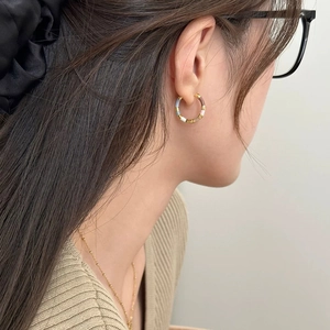 Close-up of model wearing retro enamel hoop earrings with colorful patchwork design