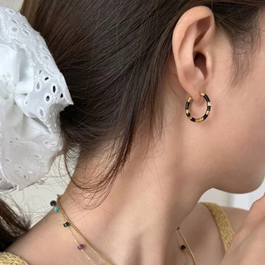 Close-up of black and gold striped enamel hoop earring worn on the earlobe