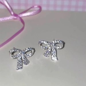 Détail de boucles d'oreilles nœud en argent avec zircone sur fond de style cadeau