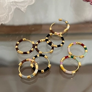 Macro detail of French vintage enamel hoop earrings with colorful gold-plated metal texture