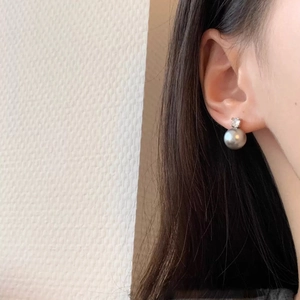 Detailed close-up of a model wearing a grey pearl earring with a sparkling zircon stud