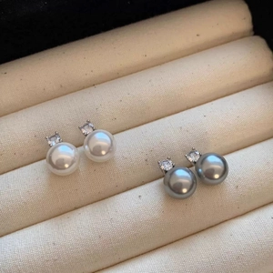 Detailed view of white and gray pearl earrings with zircon inlay in jewelry box