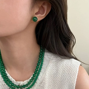 Detailed view of model wearing green chalcedony stud earrings and layered necklace