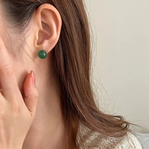 Close-up of minimalist green chalcedony stud earrings worn by a model in natural light