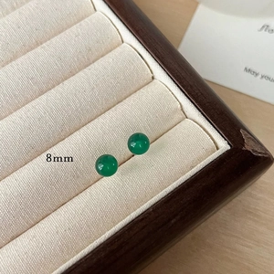 Close-up of 8mm dark green chalcedony stud earrings in a premium beige velvet box