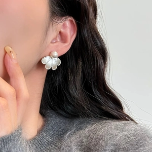 Macro detail of elegant pearl stud earring with brushed silver petal-shaped metal pendant