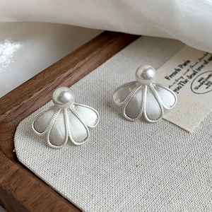 Detailed shot of brushed metal floral earrings with elegant white center pearls